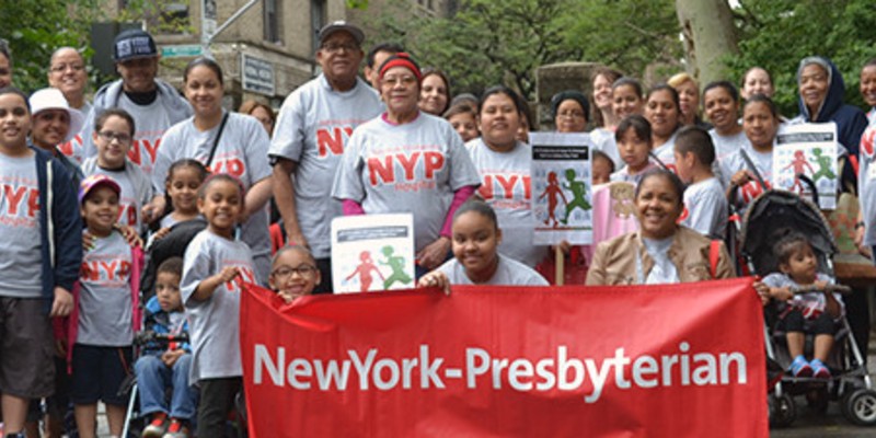Community members posing with a New York - Presbyterian banner