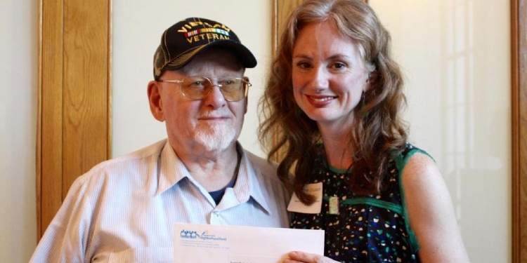 Older white man with woman holding envelope and smiling. 
