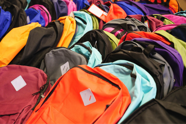 Once all of the school supply donations are unpacked and sorted, volunteers load them into backpacks. The backpacks are filled with a variety of materials appropriate for different age groups. The bags are then tagged with colored wristbands to distinguish between the age ranges. Photo Credit: Henry Danner