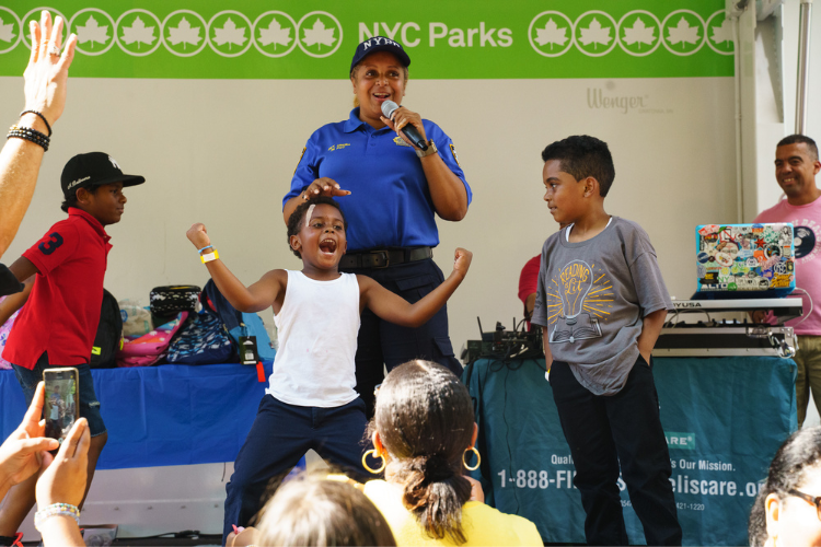 A child celebrates being selected as the winner of a dance competition during the back-to-school event in West Harlem. Photo Credit: Henry Danner