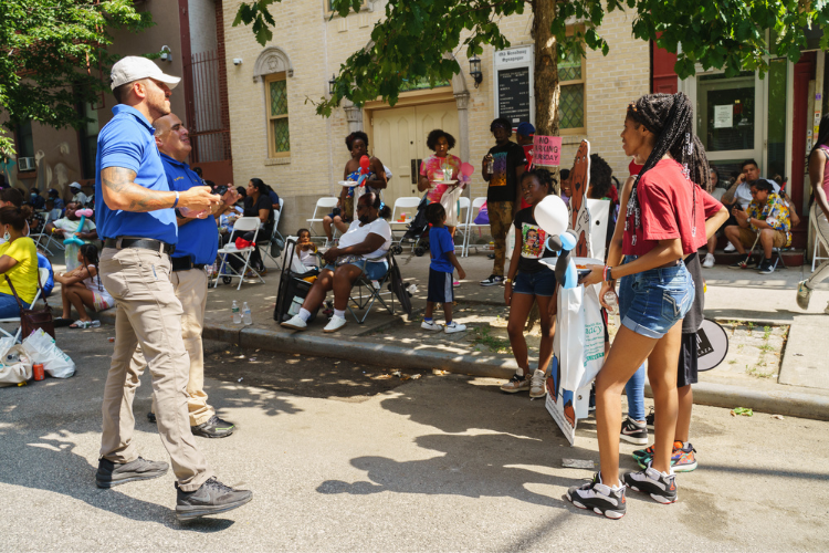 Columbia University Public Safety officers Ricardo Morales and Amin Torres take photos of youth as they pose with a cardboard cutout of McGruff the Crime Dog. Photo Credit: Henry Danner Columbia University Public Safety officers Ricardo Morales and Amin Torres take photos of youth as they pose with a cardboard cutout of McGruff the Crime Dog. Photo Credit: Henry Danner
