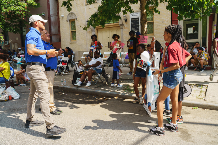 Columbia University Public Safety officers Ricardo Morales and Amin Torres take photos of youth as they pose with a cardboard cutout of McGruff the Crime Dog. Photo Credit: Henry Danner 