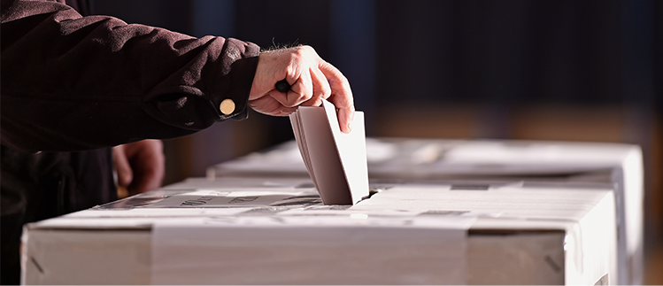 A person slips a ballot into a ballot box. 
