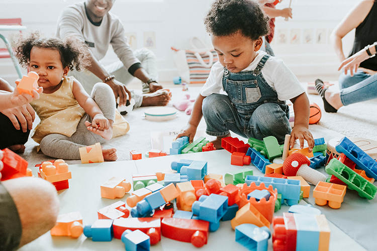 Two children play with blocks in a childcare setting.