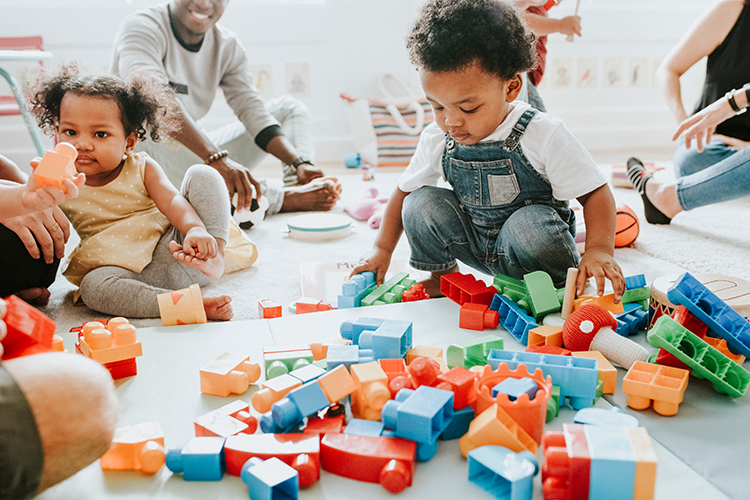 Two children play with blocks in a childcare setting. 