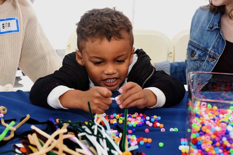 A child plays with pipecleaners and beads. 