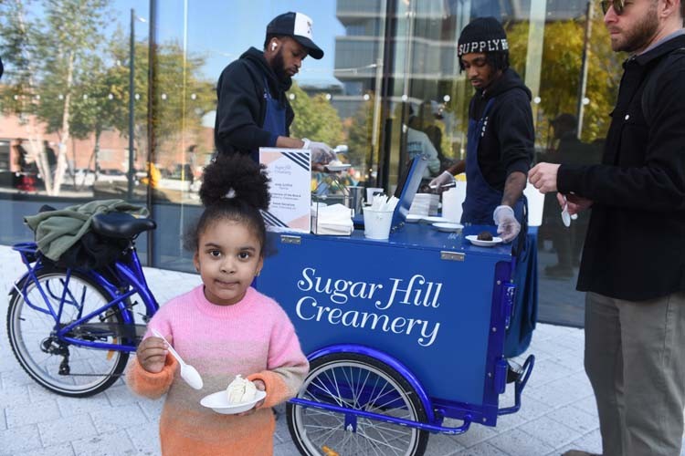A little kid enjoys a scoop of complimentary ice cream from Sugar Hill Creamery. 