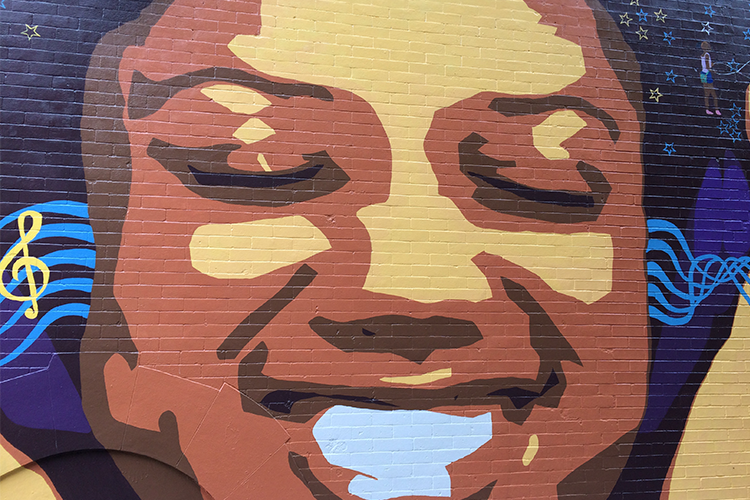 A mural of a woman smiling on 141 Street in Harlem.