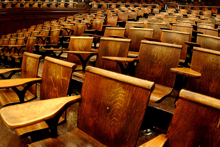 Empty wooden desks in Columbia's Havermeyer Hall. 