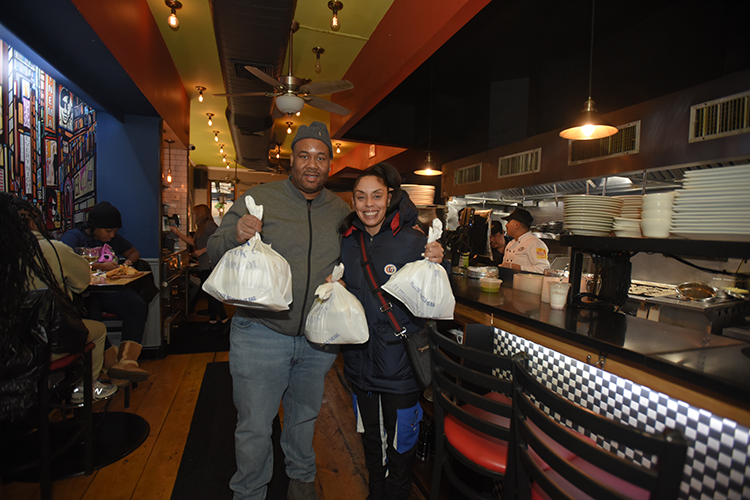 Community members pick up freshly prepared meals from Ricardo Steakhouse at Columbia University Friends and Neighbors Meal to Go program. Image by Susan Farley. Columbia neighbors smiling and grabbing food.
