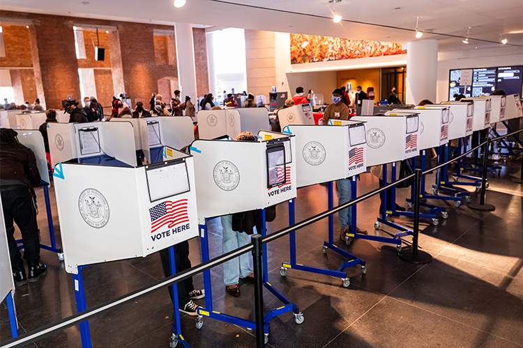 People voting behind voting dividers in New York. 