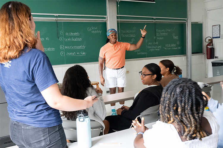 Students in the Double Discovery Center program participate in a variety of academic enrichment activities, including literature, history, writing, sociology and STEM courses over the summer and on the weekends during the academic school year. Photo by Diane Bondareff/Columbia University. Sociology Instructor Jay Brown instructs the class in front of a chalkboard with terms on it.