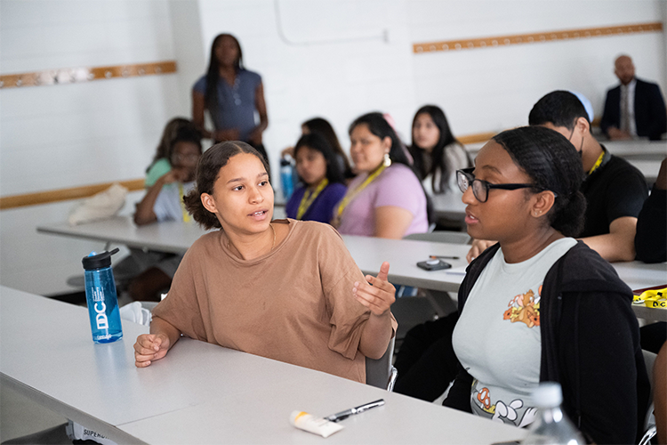 While in the Double Discovery Center program, students develop their ability to think critically and comparatively to provide a well-supported synthesis and analysis of information from multiple sources. Photo by Diane Bondareff/Columbia University. Two students speak to one another in the Double Discovery Classroom.