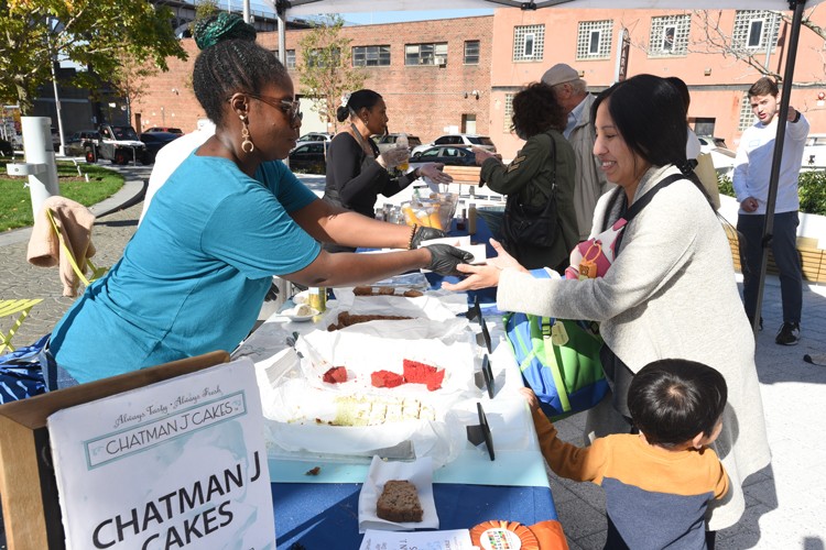 Person from Chatman J. Cakes handing a free sample to a person on Manhattanville Community Day.