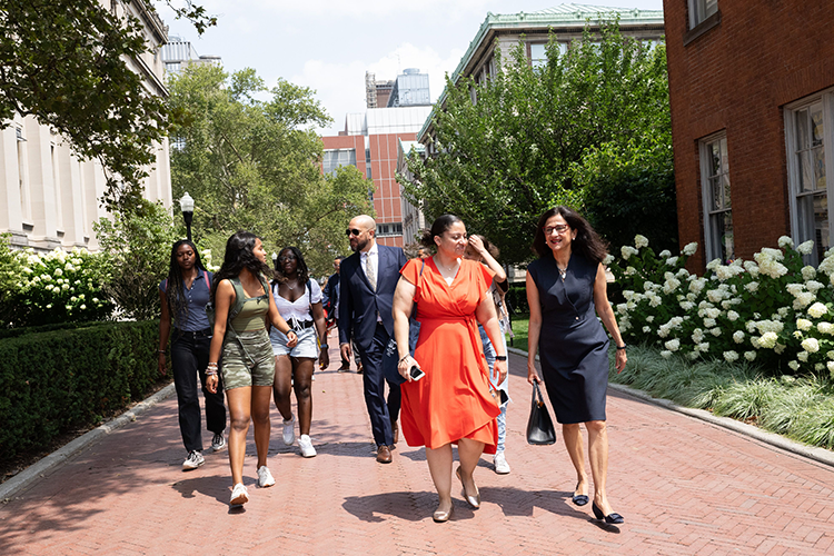 Double Discovery Center (DDC) students, Columbia College Dean Josef Sorett, DDC Executive Director Sasha Wells, and President Minouche Shafik walk through Columbia's campus on the way to a DDC class. Photo by Diane Bondareff/Columbia University. Double Discovery Center students, Columbia College Dean Josef Sorett, DDC Executive Director Sasha Wells, and President Minouche Shafik walk through Columbia's campus on a sunny day.