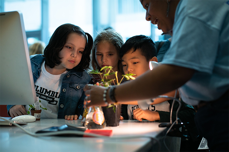 Children learn about the wonders of plants as part of Saturday Science at Community Day. Photo by David Dini. Students look at a plant.