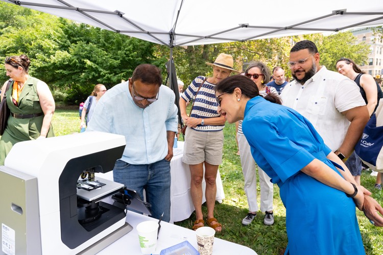 Professor Goes uses a microscope to magnify a toxic algae sample for President Shafik, Manhattan Borough Commissioner Anthony Perez, and attendees. Photo credit: Diane Bondareff Event attendees watch a science demonstration by Professor Joaquim Goes.