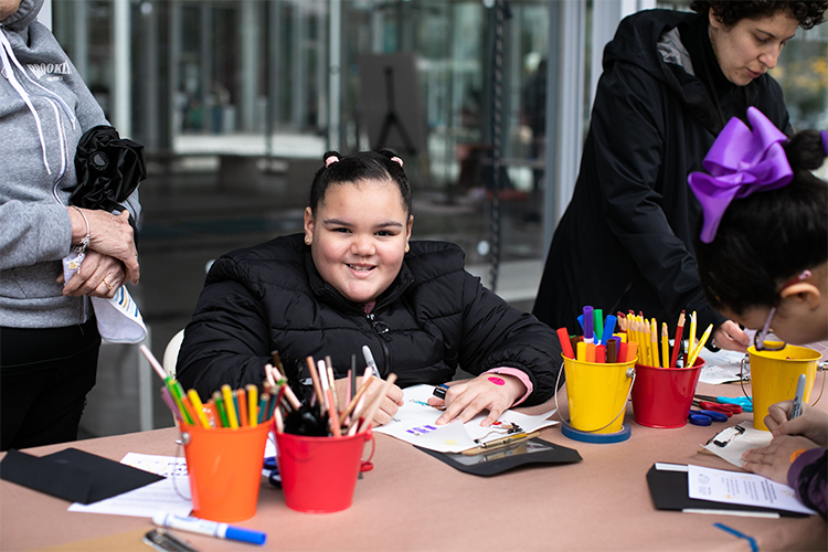 Wallach Art Gallery hosted an activity to teach kids at Community Day how artists use spatial relationships between figures and backgrounds to create impactful images. Photo by David Dini. A happy participants draws outside.