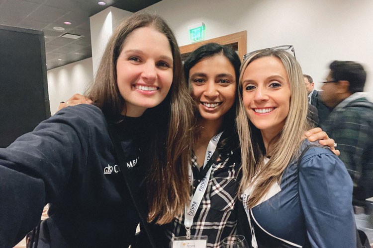 Three women pose for a photo at a conference.
