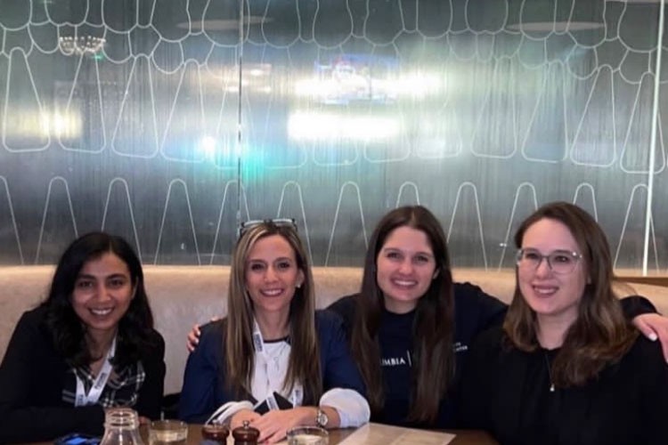 Four women part of Columbia's movement disorders team pose sitting at a table. 