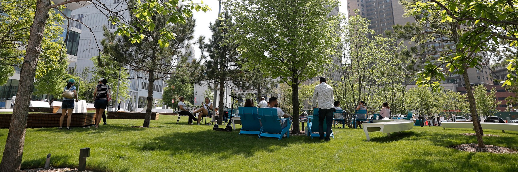 A vibrant, green area with trees, seats, and people casually lounging.