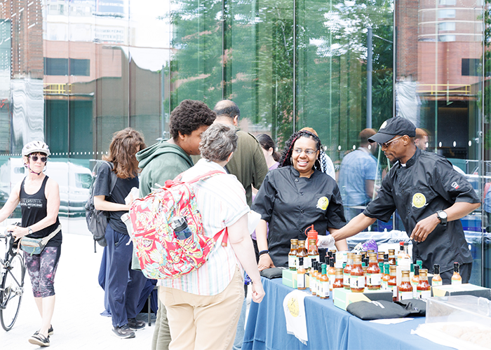 Happy Manhattanville Community Day visitors stop by Chef Marshall's hot pepper sauce table to see how much heat they can handle. Photo by Sirin Samman. Chef Marshall serves up sauces at community day.