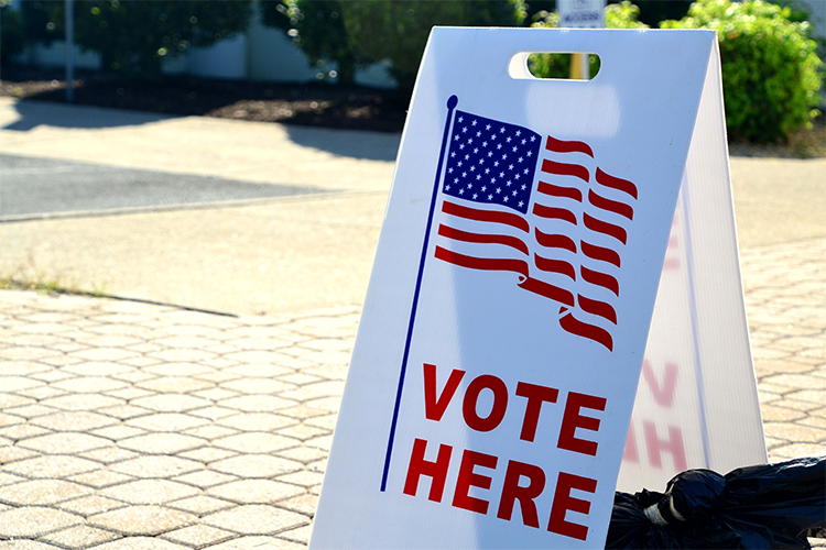 A sandwich board reading "Vote Here"