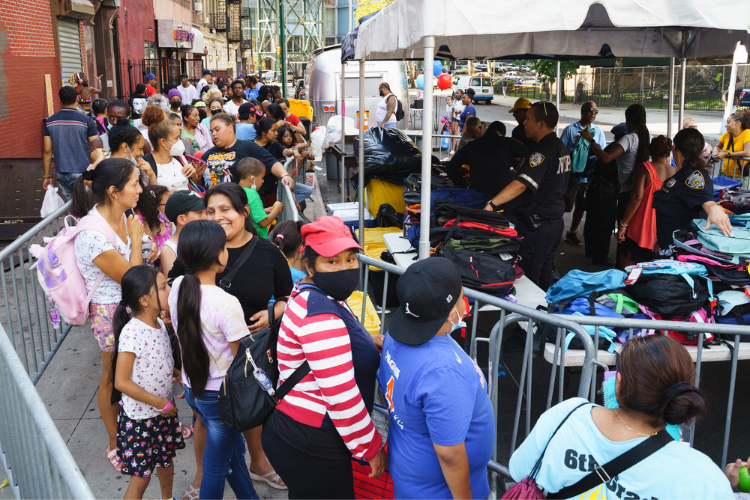 Attendees at the back-to-school event line up to receive backpacks filled with school supplies. Photo Credit: Henry Danner