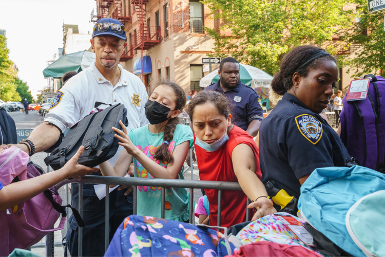  Attendees at the back-to-school event receive backpacks filled with school supplies. Photo Credit: Henry Danner