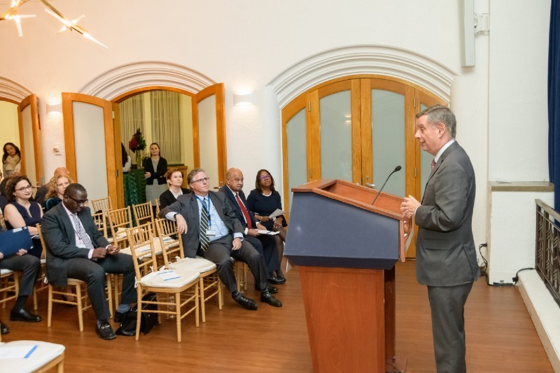 man speaking at podium to seated group