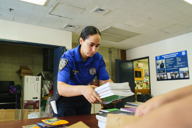 Community Affairs Officer Anna Cardenas organizes school supplies at the 26th Precinct. Photo Credit: Henry Danner