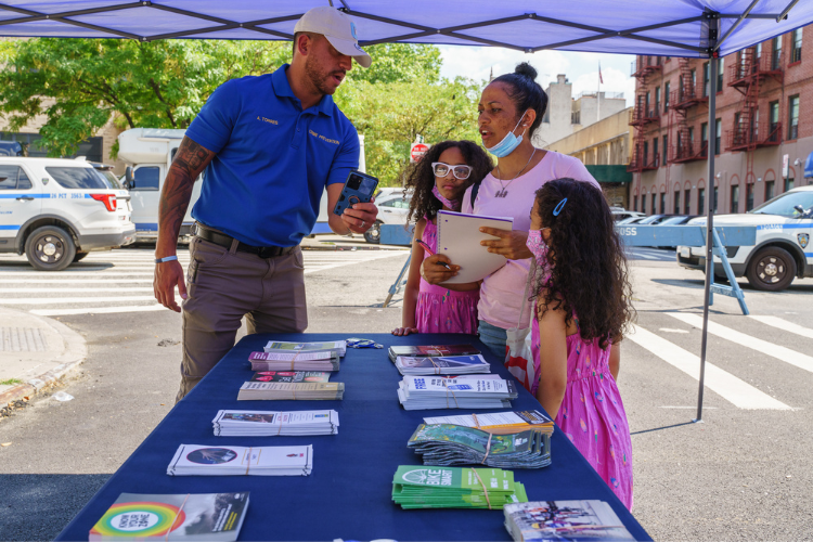 Public Safety Officer Amin Torres speaks to some community members during the annual back-to-school event in West Harlem. Torres works alongside Ricardo Morales who says that the Department of Public Safety and the 26th Precinct officers’ participation in community events helps community members to view law enforcement members as a valuable resource. Photo Credit: Henry Danner