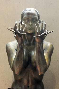 A sculpture of a woman with her hands up as planes fly into them.