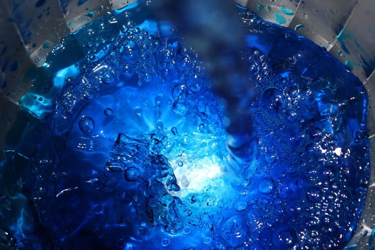 A close-up photograph of blue water in a container.