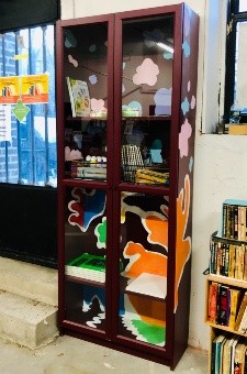 The bin is a bookshelf with glass doors