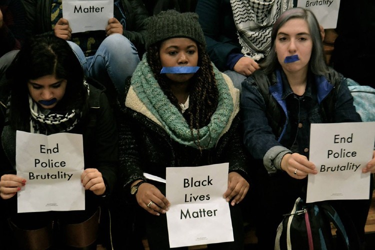 Students with signs saying black lives matter and tape over their mouths.