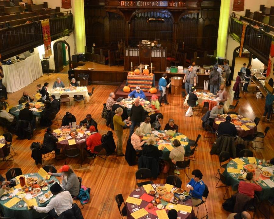 An aerial view of a meal at Broadway Community, with people seated at tables and mingling around.