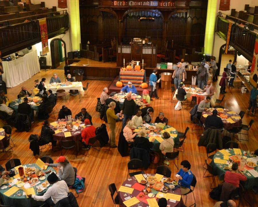 A meal at Broadway Community (Photo credit: Broadway Community) An aerial view of a meal at Broadway Community, with people seated at tables and mingling around.
