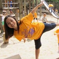 A girl in a yellow shirt plays on a playground.