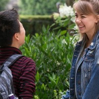 Two teenagers with backpacks laughing.