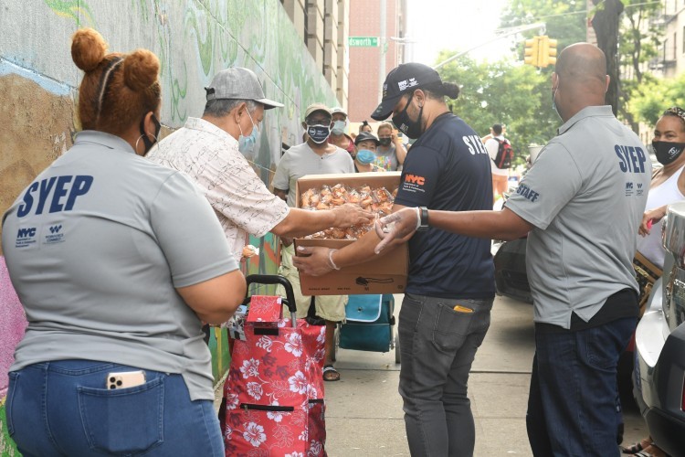 Photo credit: Eileen Barroso. A man takes a handful of fortune cookies from a box that a pantry staffer is holding out.