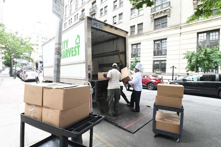 Columbia dining employees load numerous trucks using hand cart.