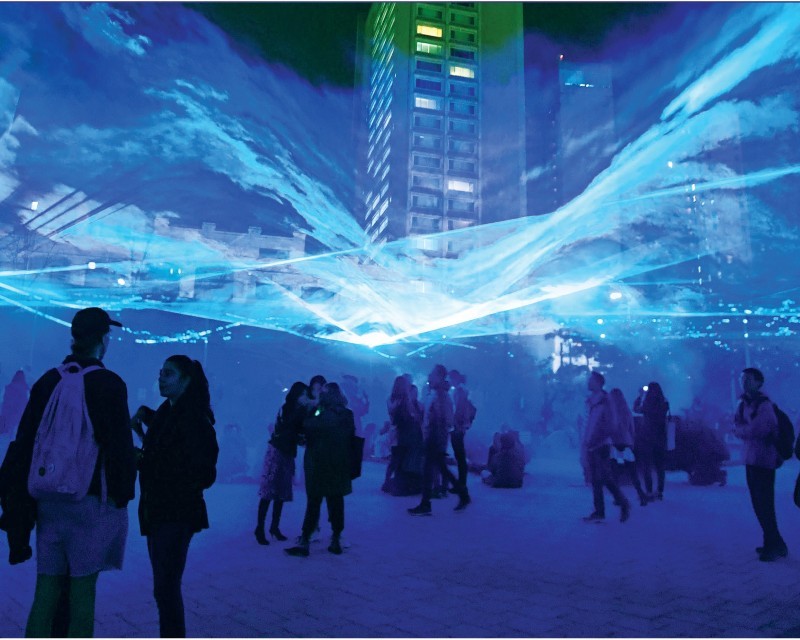 Daan Roosegaarde’s WATERLICHT at the Lenfest Center for the Arts. Photo Credit: Eileen Barroso People gathered under the LED white and blue lights, depicting water sea levels at WATERLICHT