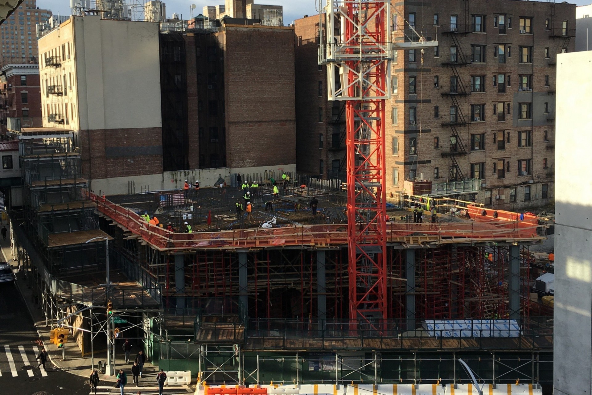 An aerial view of the 600 W. 125th Street construction site from the 125th Street subway station, with a large red crane on the site. 