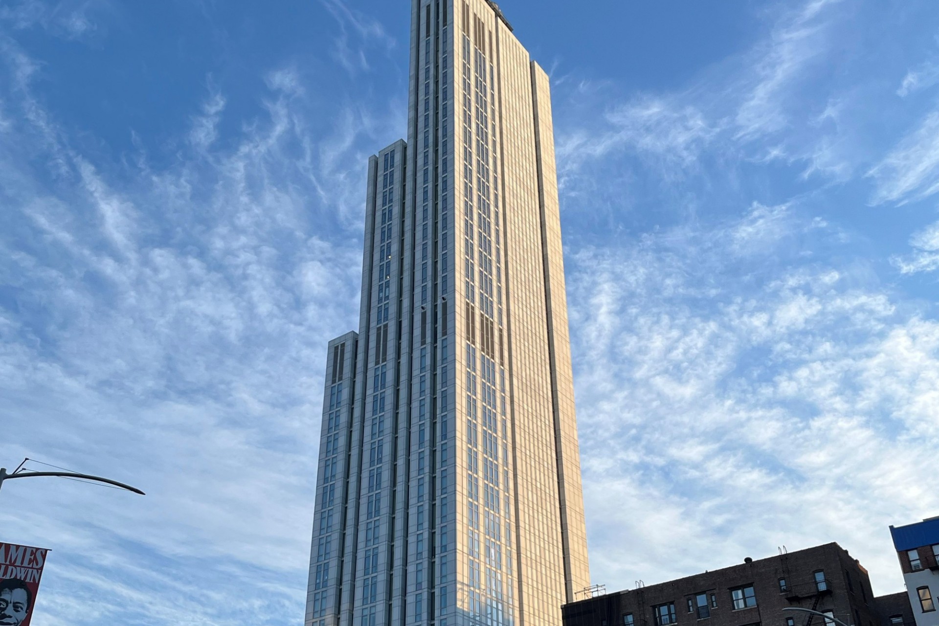 A view of the upper floors of 600 W. 125th Street on a sunny day with wispy clouds in the sky. 