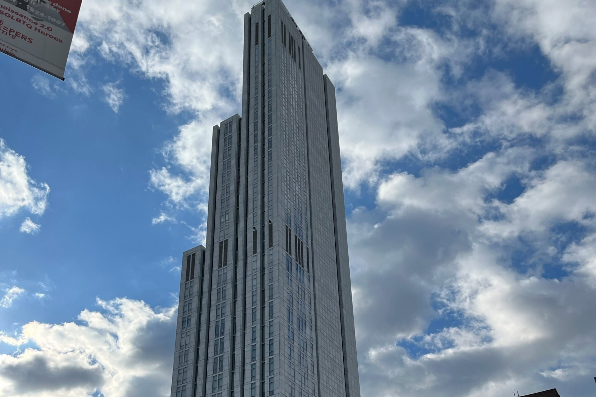 A view of the upper floors of 600 W. 125th Street on a sunny day with clouds in the sky. 