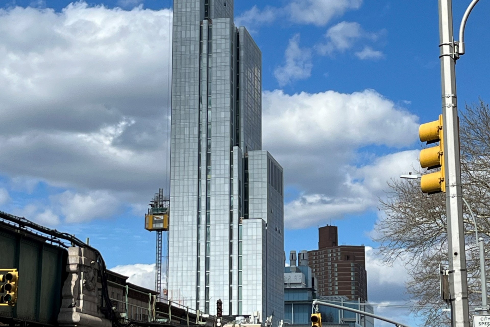 A view of the 600 W. 125th Street from the street level, with the raised subway platform running alongside and Jerome L. Greene Science Center in the background.