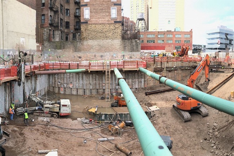 A view of the 600 W. 125th Street construction site with equipment and support pipes running across. Foundation work being performed on a construction site.