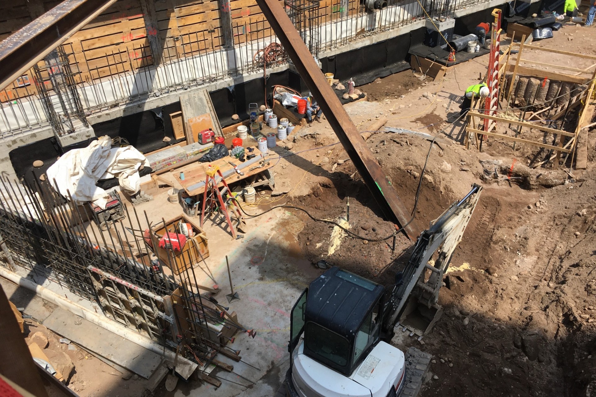 A view of the 600 W. 125th Street construction site with steel beams running across a dirt pit. 