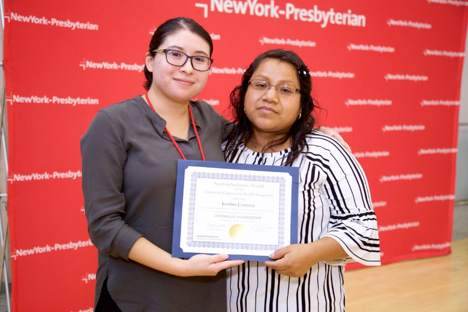 Sarah Cordero, pediatric community health worker, accompanied by the parent of a child in the CHW program receiving a certificate of completion
